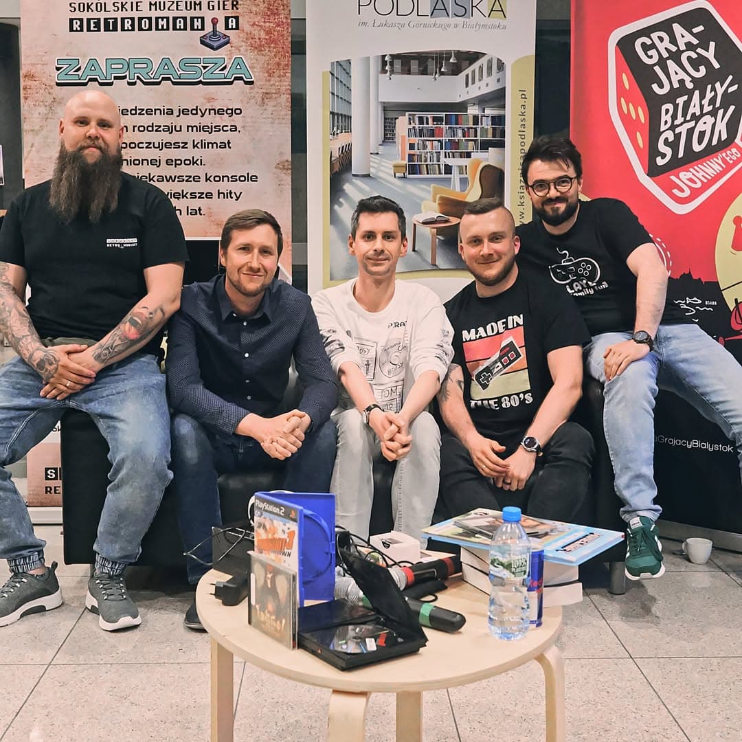 Uczestnicy spotkania planszówkowego przy stole pełnym gier
